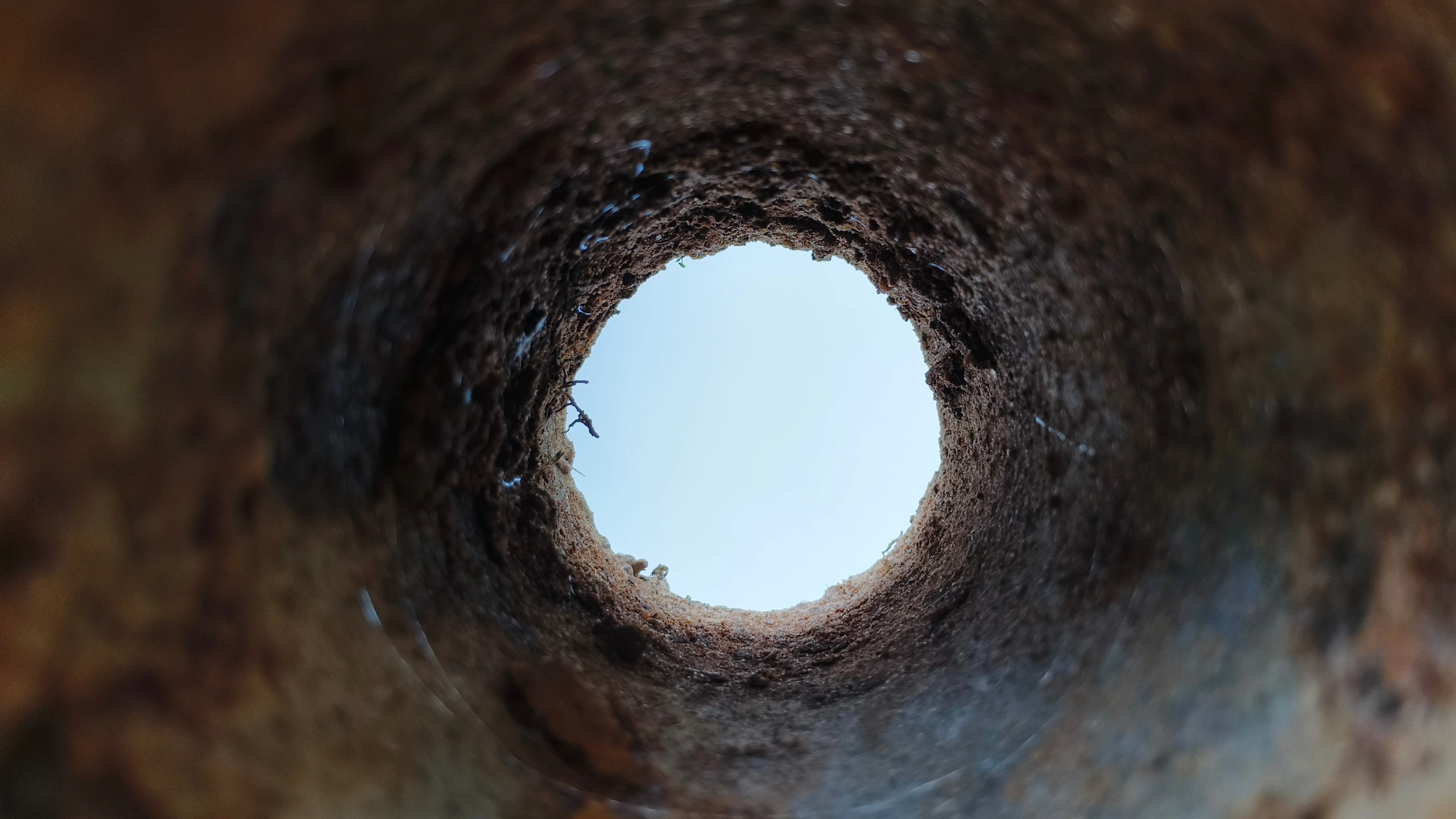 Close-up deep endless round long rusting iron metal pipe hole with oxidation or corrosion decay damage inside. Old abandoned bore well, sewer pipeline or drainage tube bad condition concept.